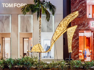 Giant high heel shoe Christmas prop illuminated with warm white Christmas lights in front of the Rodeo Drive Tom Ford storefront